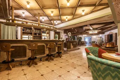 a restaurant with a bar with chairs and tables at Hotel Soreghes Gran Chalet in Campitello di Fassa