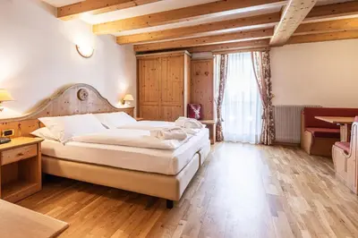 a bedroom with a large bed and a desk at Hotel Soreghes Gran Chalet in Campitello di Fassa
