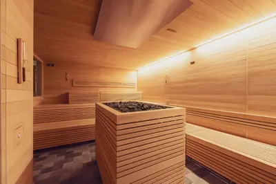 a sauna with wooden walls and a tub with rocks at Hotel Diamant Park in Campitello di Fassa