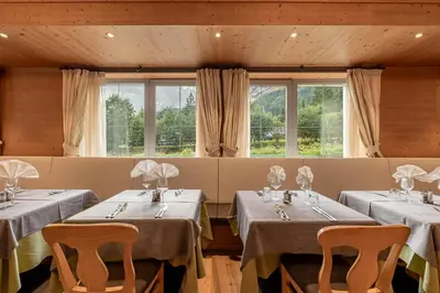 a dining room with two tables and chairs and windows at Hotel Diamant Park in Campitello di Fassa