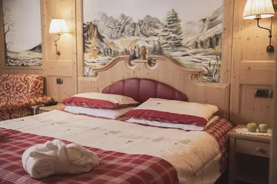 a bedroom with a bed with a red and white blanket at Hotel Rubino Deluxe in Campitello di Fassa