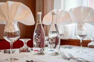 three bottles of wine sitting on a table with glasses at Hotel Grohmann in Campitello di Fassa