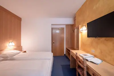 a hotel room with two beds and a flat screen tv at Hotel Grohmann in Campitello di Fassa