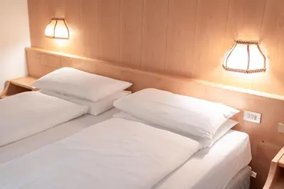 two beds in a small room with two lights at Hotel Grohmann in Campitello di Fassa
