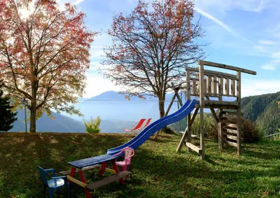 a playground with a slide and a chair at Pension Rastnerhof in Luson