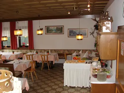 a dining room with tables and chairs with food on them at Pension Rastnerhof in Luson