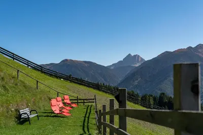 a group of chairs sitting on a hill with mountains at Pension Rastnerhof in Luson