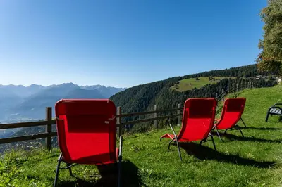 three red chairs sitting on top of a hill at Pension Rastnerhof in Luson