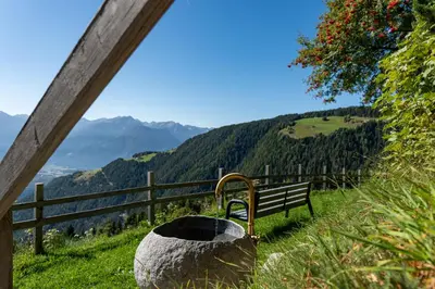 a bench sitting on top of a hill with a view at Pension Rastnerhof in Luson