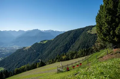 a hill with red chairs on the side of a mountain at Pension Rastnerhof in Luson