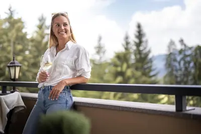 a woman standing on a balcony holding a wine glass at Hotel Baumwirt in Castelrotto