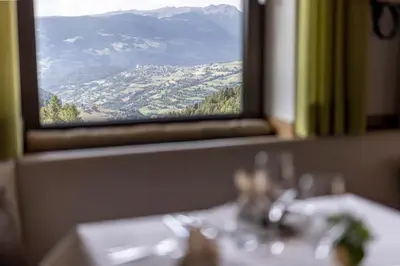 a table with a view of a mountain from a window at Hotel Baumwirt in Castelrotto