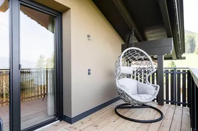 a wicker chair sitting on a deck with a porch at Hotel Baumwirt in Castelrotto