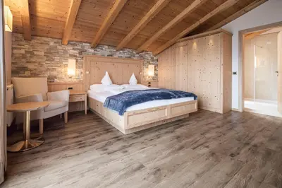a bedroom with a bed and a table and a chair at Hotel Baumwirt in Castelrotto