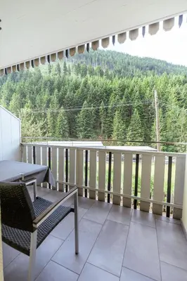 a balcony with a table and chairs and trees at Haus Angelika in Nova Levante