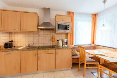 a kitchen with wooden cabinets and a table with a dining room at Haus Angelika in Nova Levante