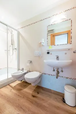 a bathroom with two toilets and a sink and a mirror at Haus Angelika in Nova Levante