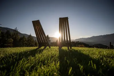 two wooden posts in the grass with the sun in the background at naturApart in Brunico