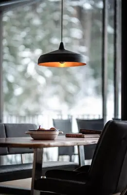 aendant light hanging over a wooden table with chairs at naturApart in Brunico