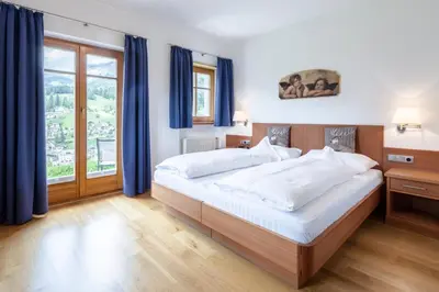 a bedroom with a large bed with blue curtains at Am Rainell Hof in Ortisei