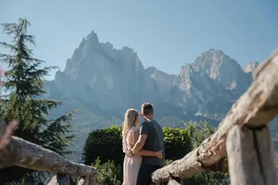 a man and a woman standing in front of mountains at Mirabell Alpine Garden Resort & Spa in Siusi