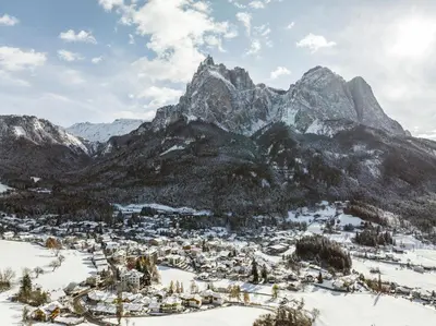 a town in the snow with mountains in the background at Mirabell Alpine Garden Resort & Spa in Siusi