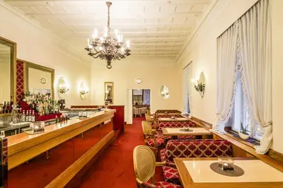 a restaurant with couches and tables and a chandelier at Grand Hotel Bellevue - adults only in Merano