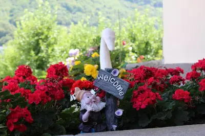 a flower bed with red flowers and a garden statue at Gruberhof in Postal