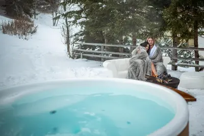 a woman sitting on a couch in the snow next to a bath tub at Sporthotel Teresa in Badia