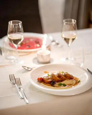 a white plate of food on a table with wine glasses at Sporthotel Teresa in Badia
