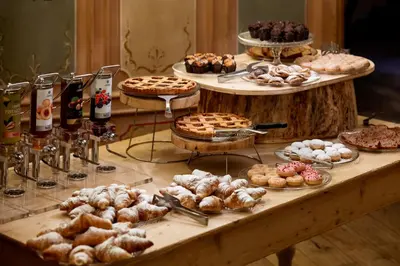 a table filled with different types of pastries and pies at Sporthotel Teresa in Badia