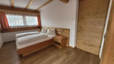a bedroom with a bed and a wooden door at Apartments Ingrid in La Valle