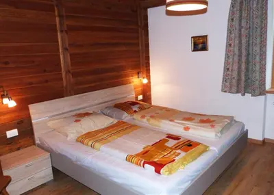 two beds in a room with wooden walls at Apartments Ingrid in La Valle