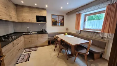 a kitchen with a wooden table and a dining room at Apartments Ingrid in La Valle