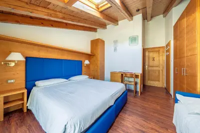 a bedroom with a blue bed and a desk at Barisetti Sport Hotel in Cortina dʼAmpezzo