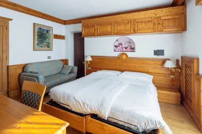 a bedroom with a bed and a chair and a table at Barisetti Sport Hotel in Cortina dʼAmpezzo