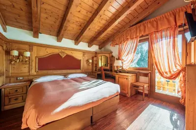 a bedroom with a large bed and a wooden ceiling at Barisetti Sport Hotel in Cortina dʼAmpezzo