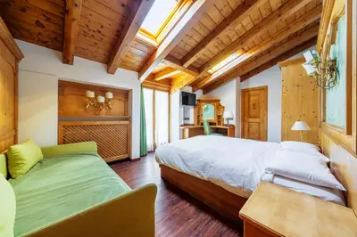 a bedroom with a bed and a couch in it at Barisetti Sport Hotel in Cortina dʼAmpezzo