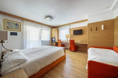 a hotel room with two beds and a desk at Barisetti Sport Hotel in Cortina dʼAmpezzo