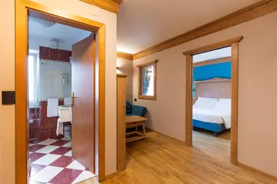 a room with a bedroom and a bed and a mirror at Hotel Medil in Campitello di Fassa