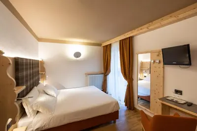 a hotel room with a bed and a mirror at Hotel Medil in Campitello di Fassa