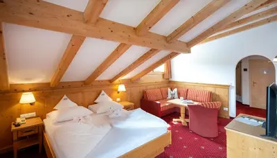 a bedroom with a bed and a couch and a table at Hotel Bellavista in Alpe di Siusi
