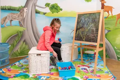 a little girl playing with toys in front of a mural at Hotel Alpino in Varena