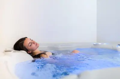 a woman is sitting in a bath tub at Hotel Alpino in Varena