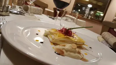 a plate of food on a table with a glass of wine at Hotel Alpino in Varena
