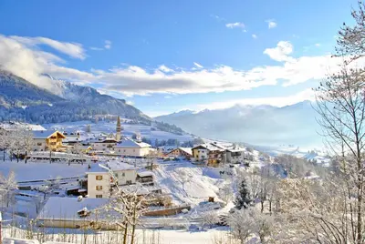 a village in the snow with mountains in the background at Hotel Alpino in Varena