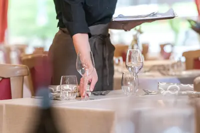a woman is holding two wine glasses on a table at Hotel Alpino in Varena