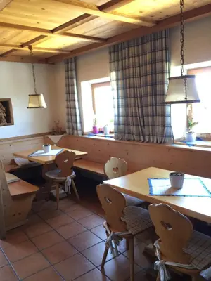 a restaurant with wooden tables and chairs and a window at Pension Höggerhof in Nova Ponente