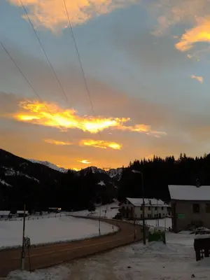 a sunset over a road with snow on the ground at Hotel Bucaneve in Moena