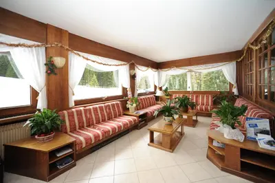 a living room with red leather couches and windows at Hotel Bucaneve in Moena